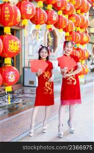 Asian Two girl wearing red traditional Chinese cheongsam decoration holding red envelopes in hand and lanterns with the Chinese text Blessings written on it Is a Fortune blessing for Chinese New Year