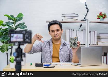 Asian Vlogger man dissatisfied old technology of hard disk when sharing knowledge to audience via camera by social media channel, camera taking video and live with laptop,vlog and Influencer concept