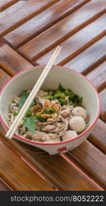 Asian white noodles. Asian white noodles with pork and vegetables in bowl over wooden background