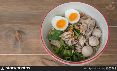 Asian white noodles with pork and vegetables in bowl over wooden background, , Free space for text