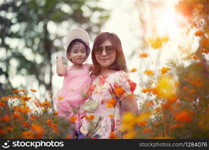 asian woman and little girl happiness emotion in yellow cosmos flower blooming field