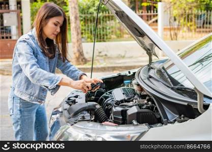 Asian woman and using smartphones to send engine pictures and send to assistance after a car breakdown on street. Concept of vehicle engine problem or accident, emergency help from Professional