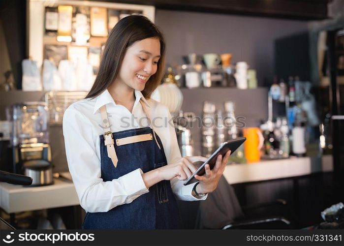 Asian woman barista smiling with tablet in her hand,Female employees are taking orders from online customers