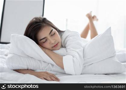 Asian woman Beautiful young smiling woman sitting and sleeping in white bed and stretching in the morning at bedroom after waking up in her bed fully rested