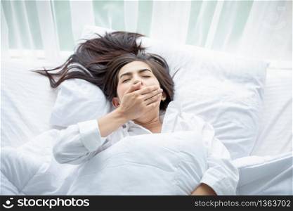 Asian woman Beautiful young smiling woman sitting and sleeping in white bed and stretching in the morning at bedroom after waking up in her bed fully rested