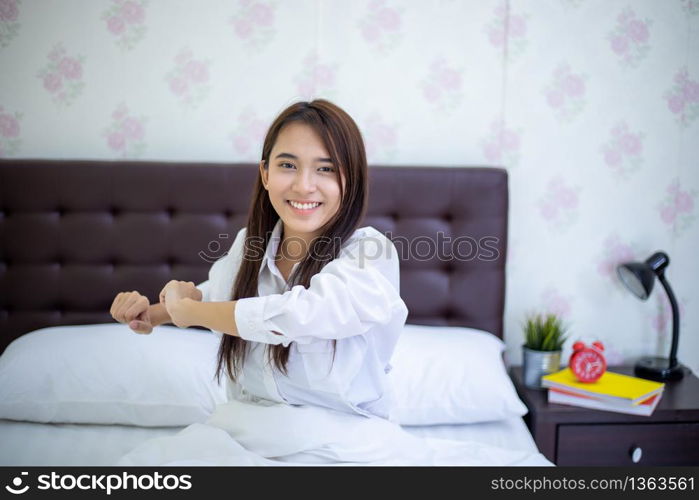 Asian woman Beautiful young smiling woman sitting on bed and stretching in the morning at bedroom after waking up in her bed fully rested