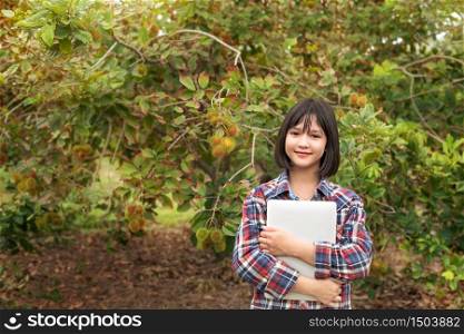 Asian woman checking report organic fruit in orchard , agriculture business, healthy food concept. Asian woman checking report organic fruit in orchard