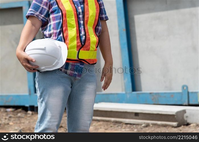 Asian woman civil construction engineer worker or architect with helmet and safety vest happy working at a building or construction site. Woman construction engineer at construction site