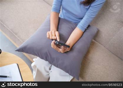 Asian Woman controlling smart home. mobile phone with smart home app in living room. touch screen ai technology. Remote home control system