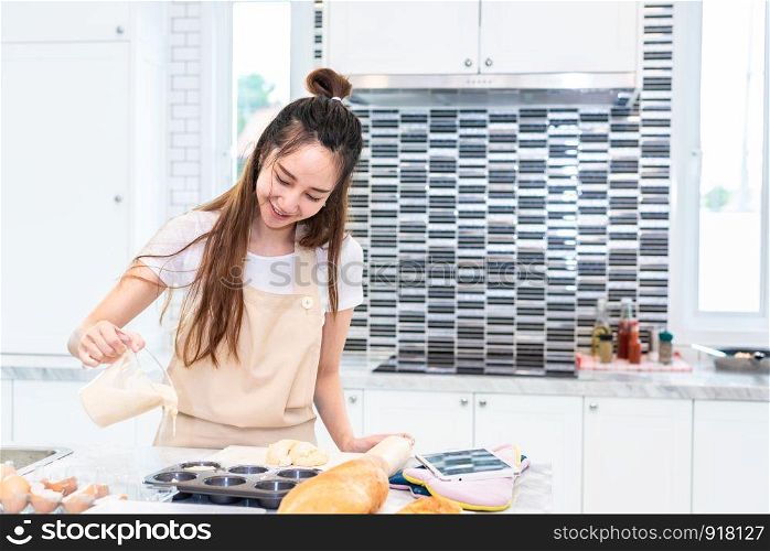 Asian woman cooking and baking cake in kitchen alone happily. People and lifestyles concept. Food and drink theme. Interior decoration theme.
