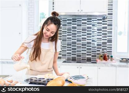 Asian woman cooking and baking cake in kitchen alone happily. People and lifestyles concept. Food and drink theme. Interior decoration theme.