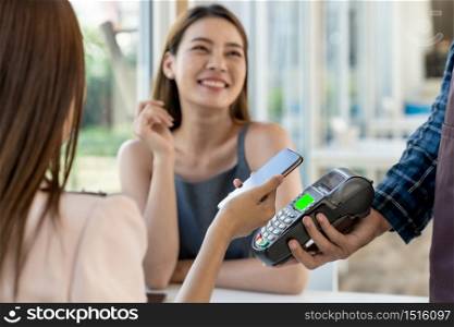 Asian woman customer moblie phone to make online contactless mobile payment after eating out in new normal social distance restaurant. Online contactless and technology concept.