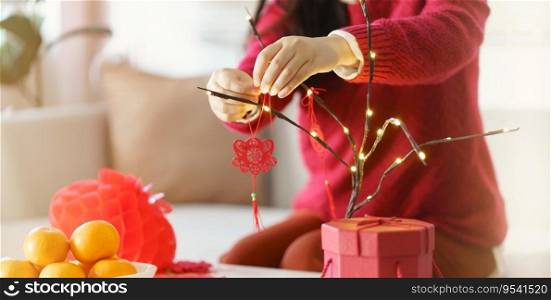 Asian Woman decorated house for Chinese New Year Celebrations. putting traditional pendant to the Chinese Lunar New Year for good luck. Chinese word means blessing.