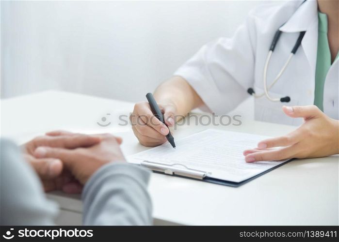 Asian Woman Doctor discussing and consulting with Elderly man patient about his information symptoms in white medical room at the hospital. Disease, illness, Flu, Covid-19, Coronavirus, Pandemic.