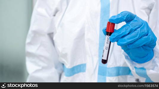 Asian woman doctor in personal protective suit holding test tube with blood sample collected from quarantine covid-19 patient for testing coronavirus. Coronavirus, covid-19 and laboratory concept.