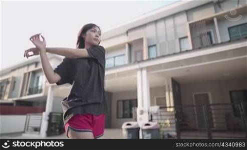 Asian woman doing shoulder arms stretching before exercise ,muscle injury prevention, heating up body before running, human metabolism and immune system, outside neighborhood street exercising routine