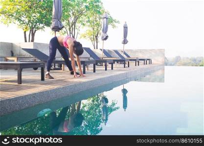 Asian woman doing yoga near swimming pool. Healthy and Beauty concept