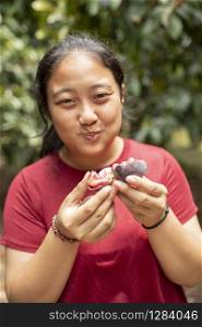 asian woman eating fresh mangosteen in fruit plantation field
