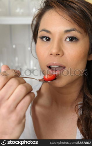 Asian woman eating strawberries