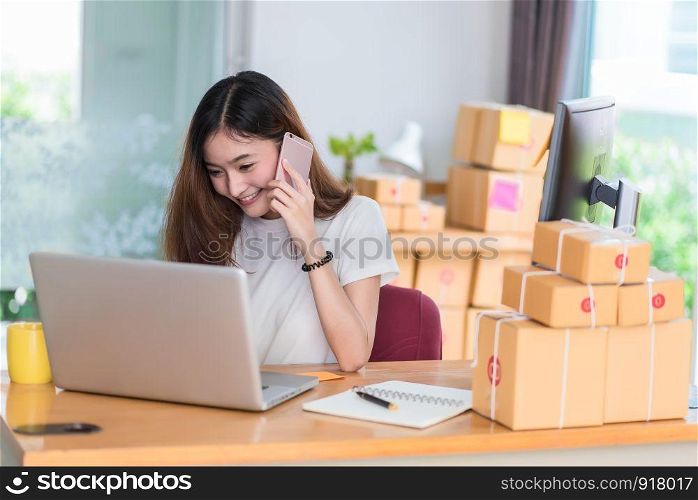 Asian woman enjoy herself while using internet on laptop and phone in office. Business and marketing and part time concept. Online shopping and business success theme. Happy mood doing working job.