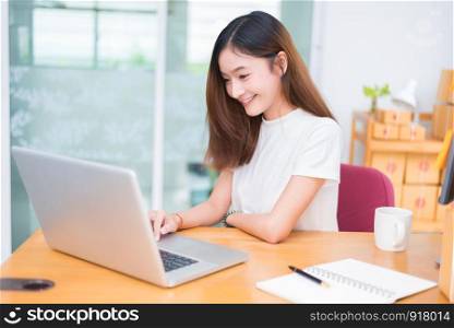 Asian woman enjoy herself while using laptops and internet in office. Business and marketing and part time concept. On line shopping and business success theme. Happy mood doing working job.