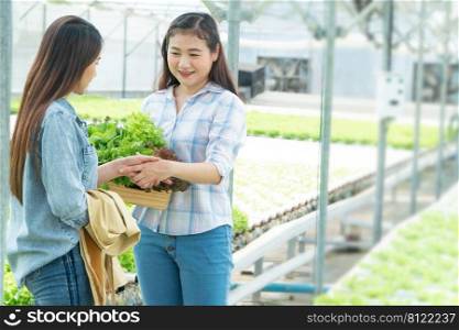 Asian woman farmer holding a vegetable basket and shake hands with partners after the agreement succeed. Concept of high quantity control and Quality for a hydroponic farm