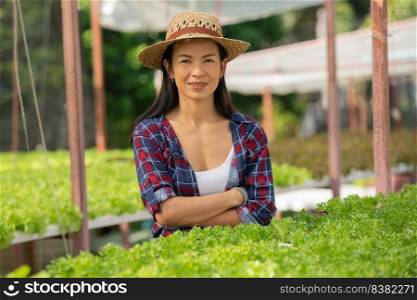 Asian  woman farmers working in vegetables hydroponic farm with happiness. Portrait of woman farmer checking quality of green salad vegetable with smile in the green house farm.