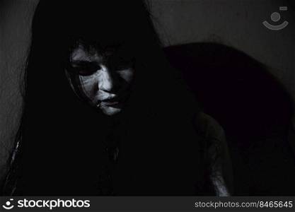 Asian woman ghost or zombie horror creepy scary close up she face and hair covering the face her eye looking to camera at night, Halloween day concept, in dark tone