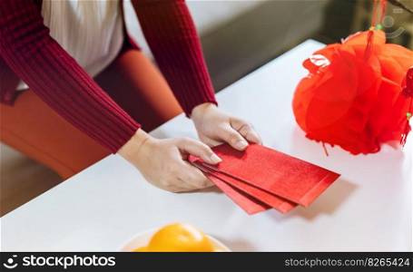 Asian Woman giving red envelope for Lunar New Year celebrations. Hand hold red packet.