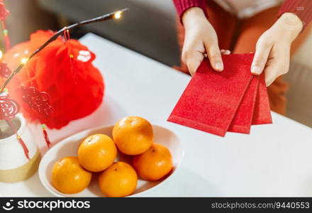 Asian Woman giving red envelope for Lunar New Year celebrations. Hand hold red packet.