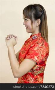 Asian woman greeting in traditional Chinese or cheongsam with hand lift welcome expression and lucky in chinese new year celebration in red golden style