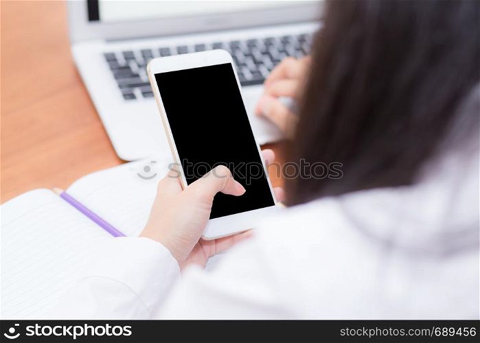 Asian woman hand holding a white phone with screen above on desk, girl using mobile with laptop, communication online digital concept.