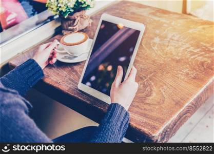 asian woman hand holding tablet and using tablet in coffee shop with vintage toned.