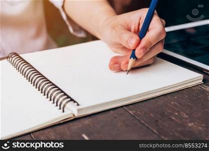 asian woman hand writing pencil on notebook in coffee shop with vintage toned