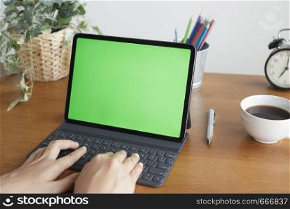 Asian woman hands are using tablet has a green screen on the desk