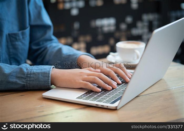 Asian woman hands using laptops on table at cafe