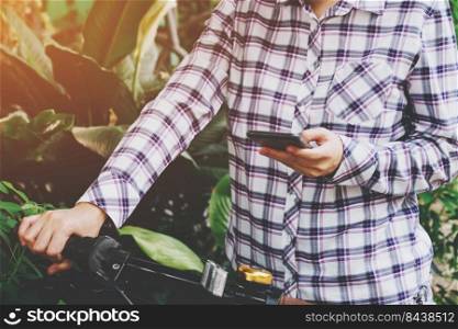 Asian woman holding and using phone on bicycle with vintage toned.