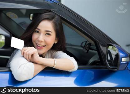 Asian woman holding personal accident insurance card and sitting in blue car
