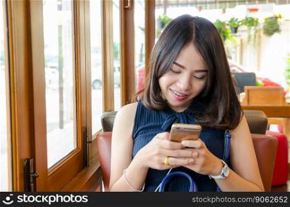 asian woman holding smartphone with smile face  at coffee cafe