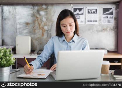 Asian woman holding yellow pencil in hand and using laptop, Female working in office desk