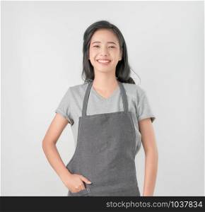 Asian woman in apron and standing and looking forward on gray background. Small business Concept