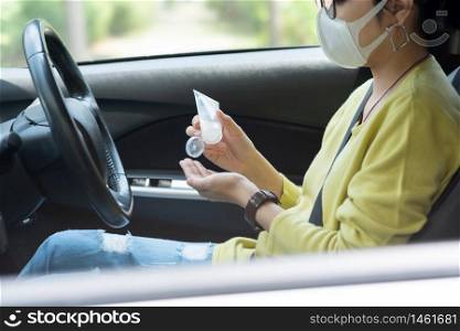 Asian Woman in green or yellow shirt wear protective mask applying hand sanitizer gel on her palms for prevent coronavirus or Covid 19 before driving a car. Cleaning, Antiseptic, Hygienic, Healthy