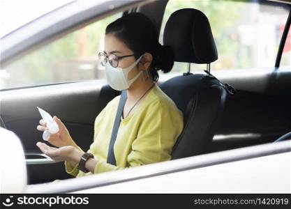 Asian Woman in green or yellow shirt wear protective mask using hand sanitizer gel on her palms for prevent coronavirus or Coronavirus before driving a car. Cleaning, Antiseptic, Hygienic, Healthy and Health care