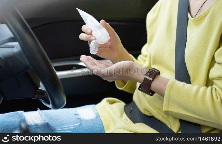 Asian Woman in green or yellow shirt wear protective mask using hand sanitizer gel on her palms for prevent coronavirus or Coronavirus before driving a car.