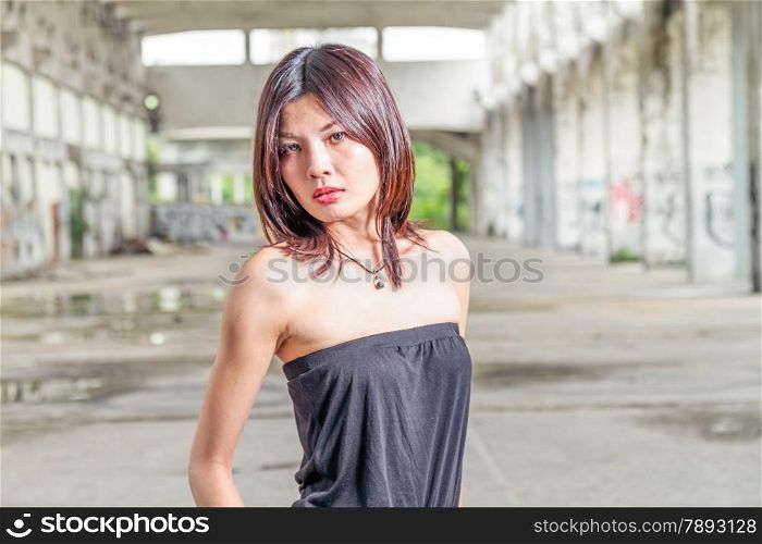 Asian woman in old derelict building looking at camera