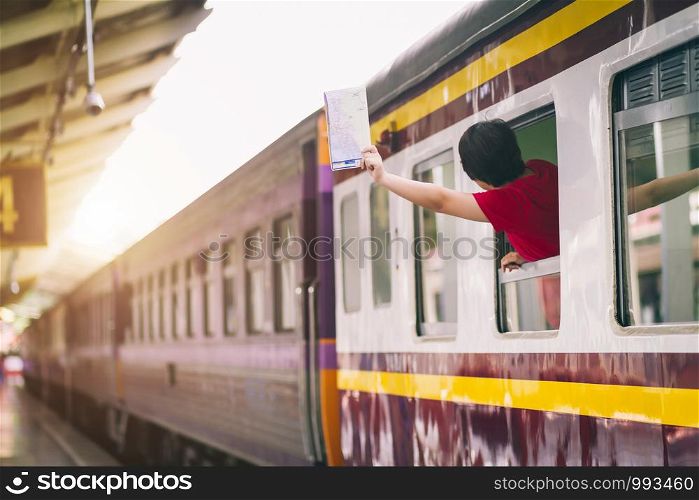 Asian woman in red dress holding a map and hand up say hello on the train. travel railway station travel.