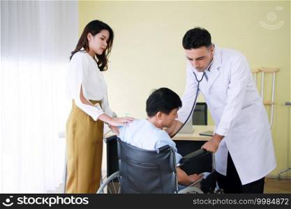 Asian woman is caring and Take the old father sitting on wheelchair and illness health for to see a doctor and Checked by Stethoscope at hospital in Thailand
