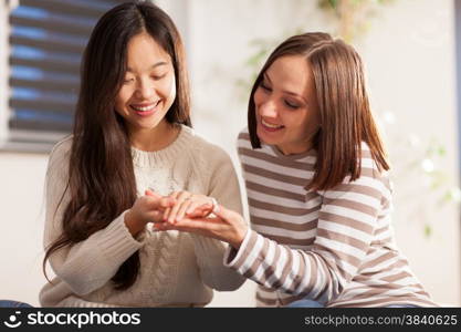 Asian woman is showing her wedding ring to her friend at home