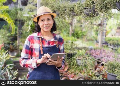 Asian woman is using a tablet to check the vegetation in the Ornamental plant shop, Small business concept