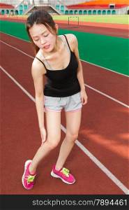 Asian woman jogger holding hurt leg on track